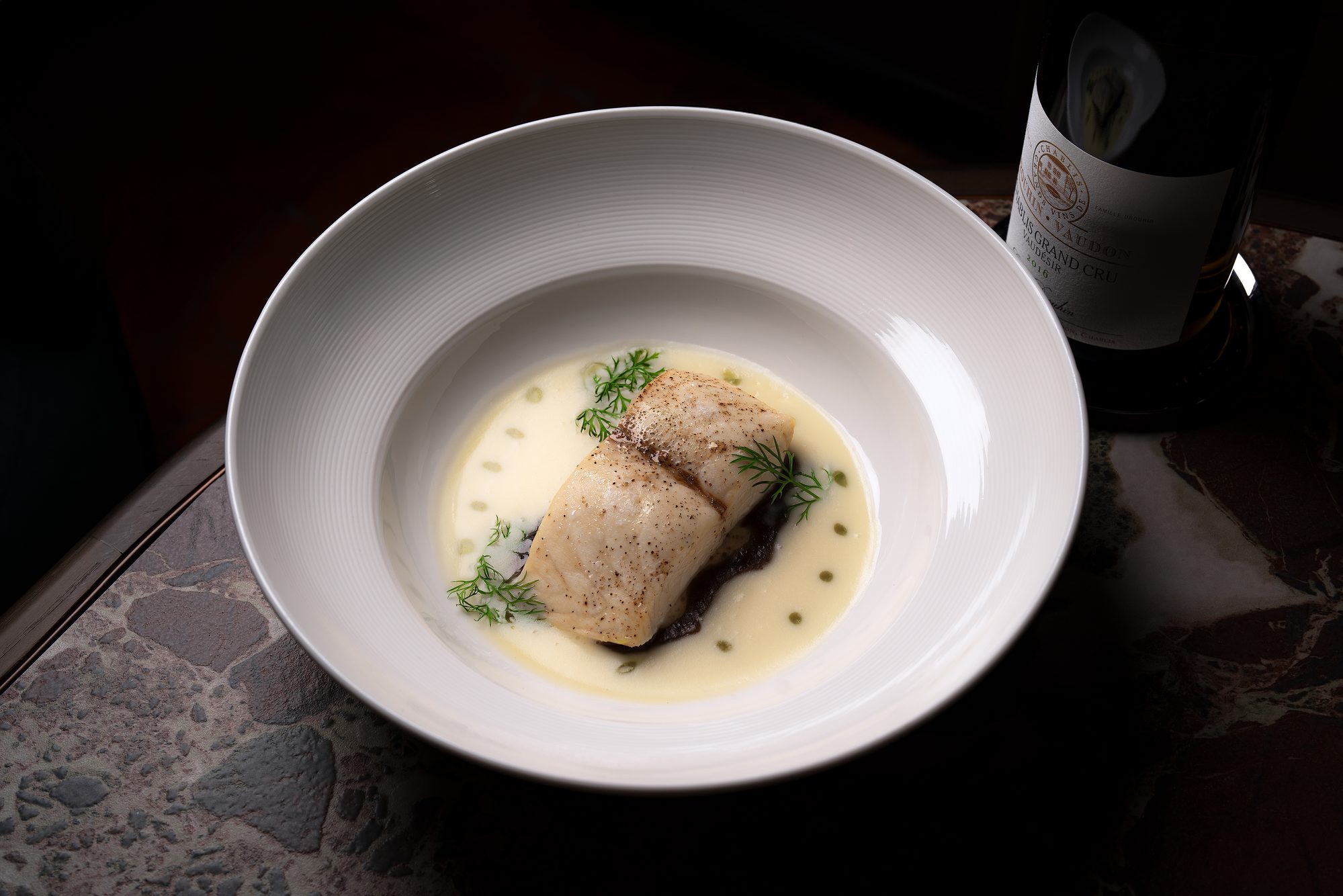 A plated fillet of fish in a pale butter sauce