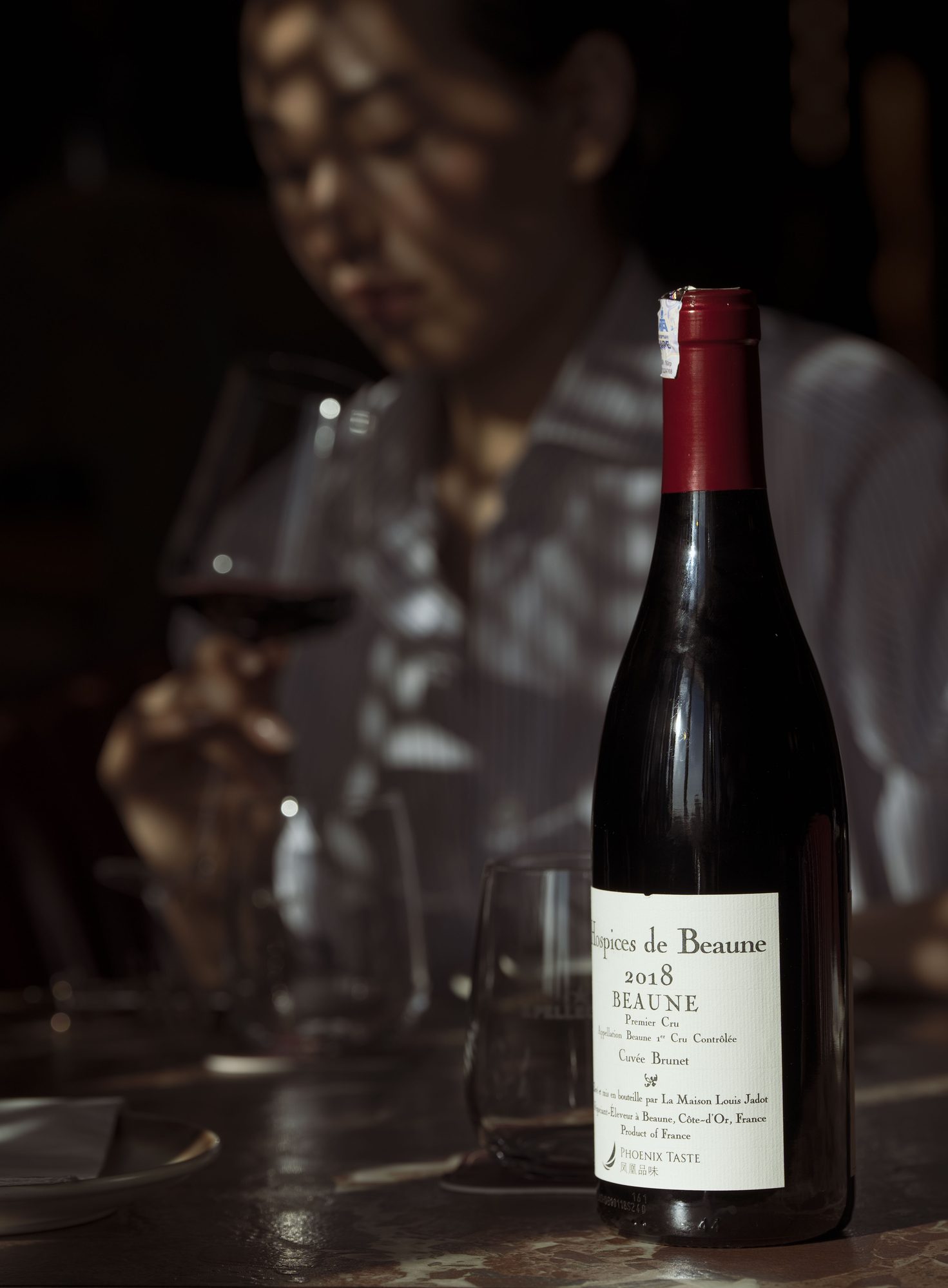 A single bottle of Beaune lit against a dark wall