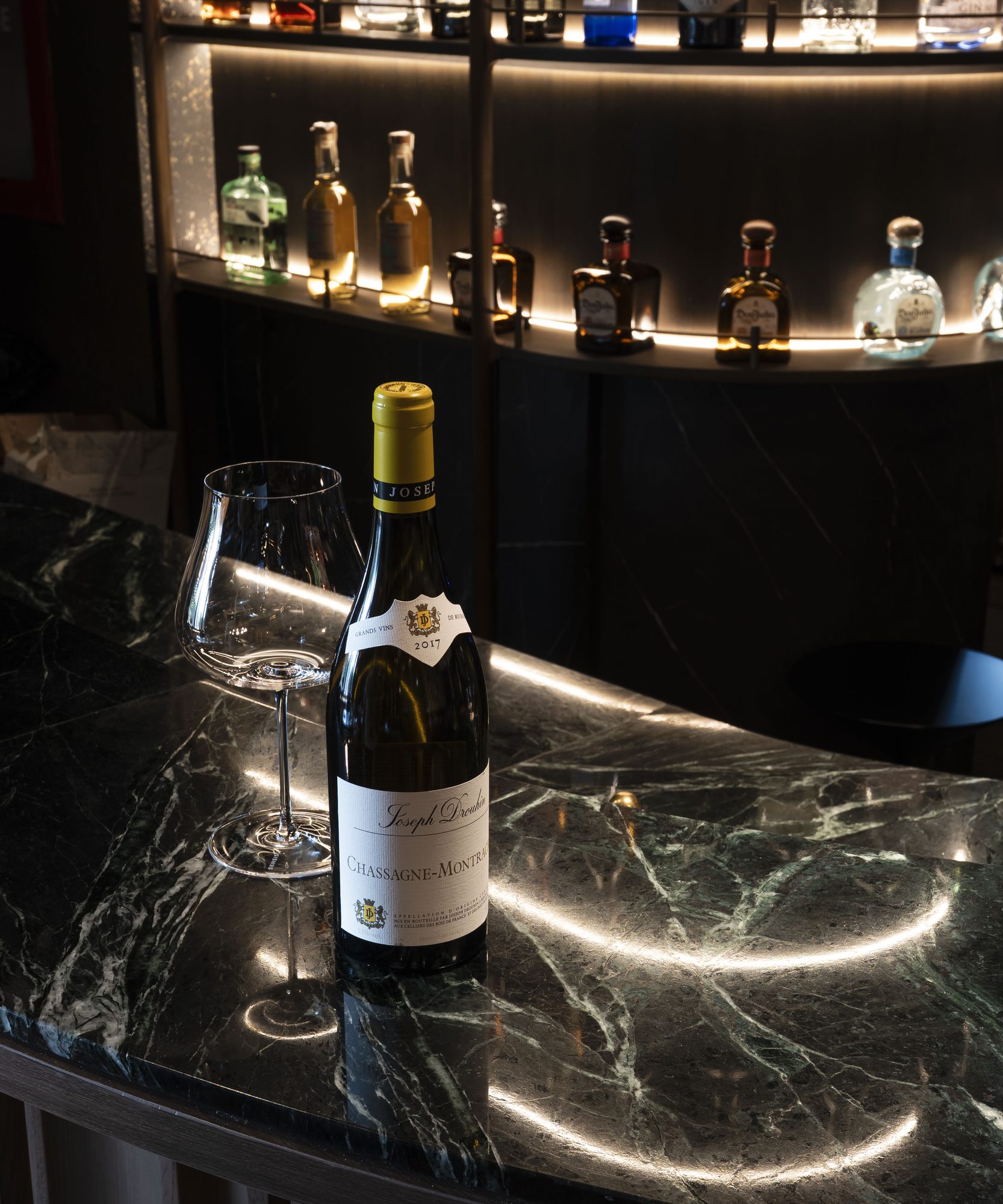 An open bottle of red Burgundy and a glass on green marble