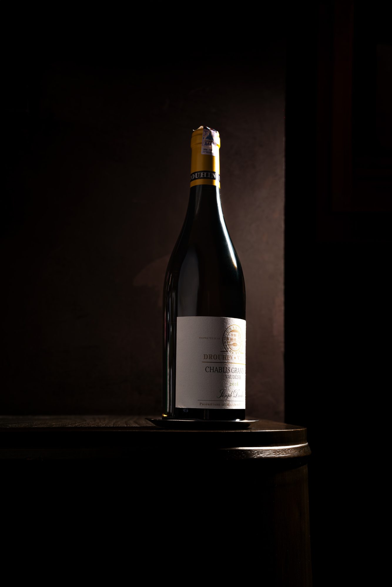 A sommelier lifting a bottle of Beaune from a backlit rack