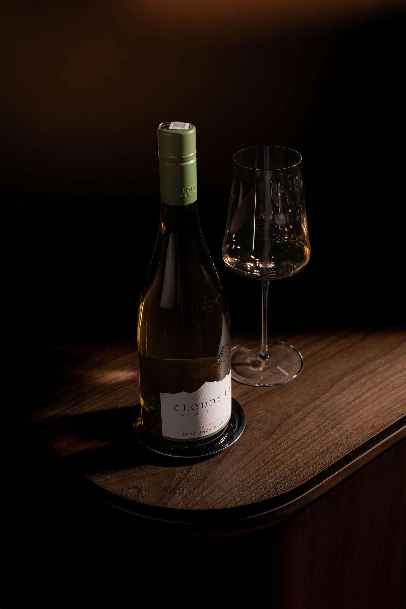 A chilled white bottle and glass on a walnut table
